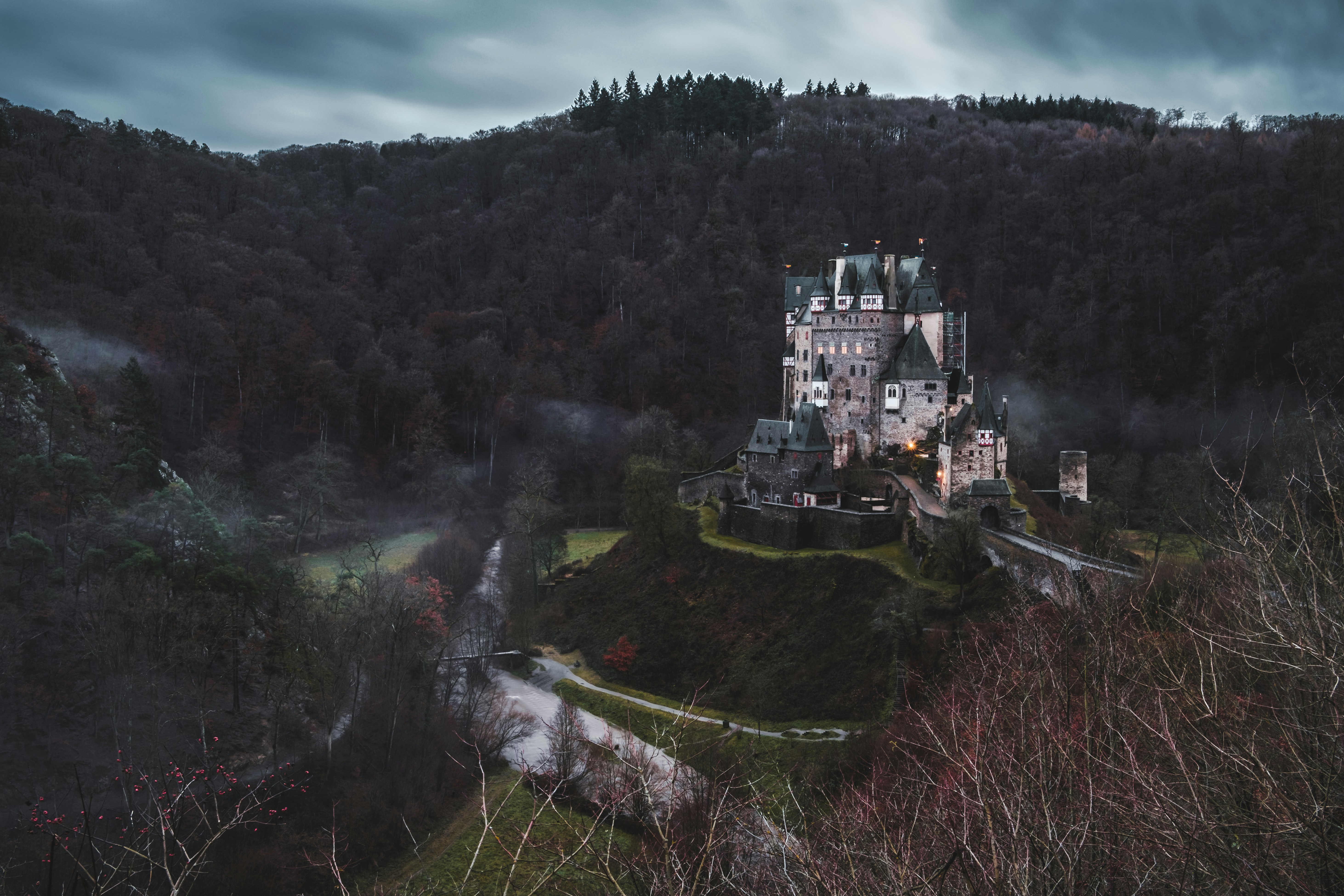 gray concrete castle surrounded by trees under gray skies